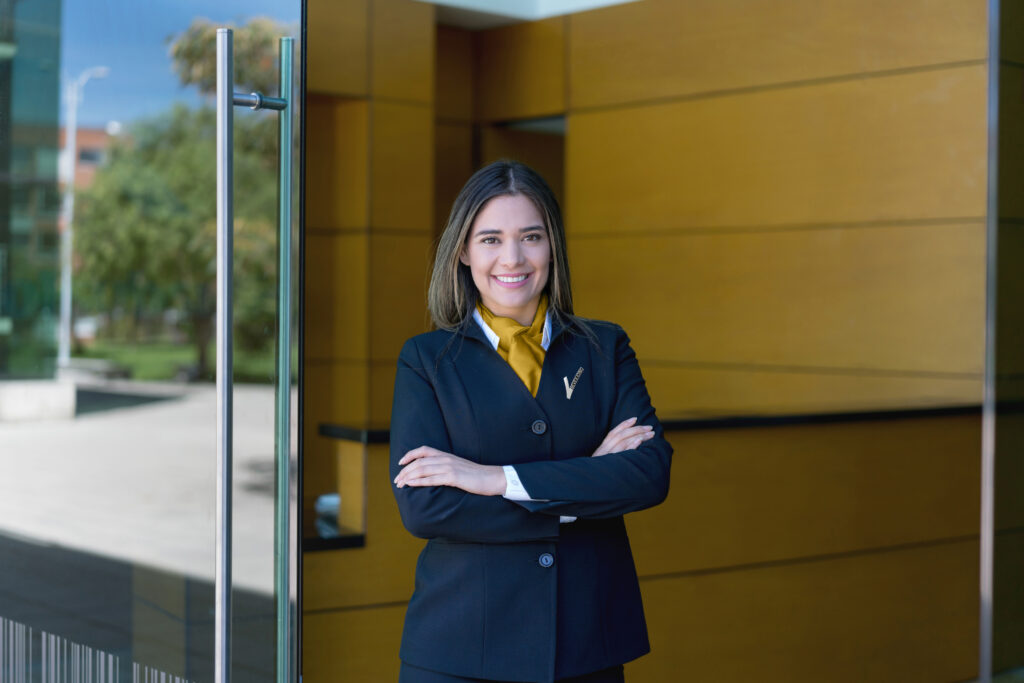 Latin american female hotel manager standing at the entrance with arms crossed looking at camera very happy
